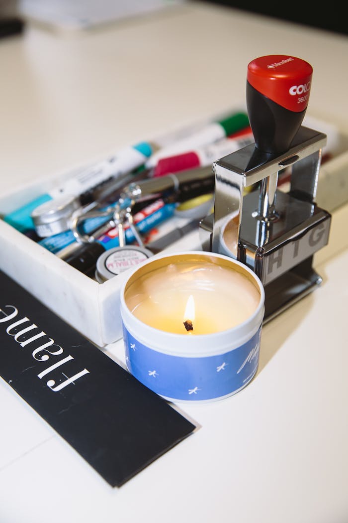 Close-up of office supplies including a candle and stamp in a workspace setting.